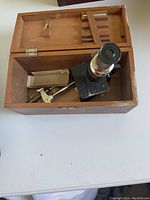 Open wooden case containing the microscope and some accessories