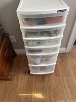 Closed view of the white plastic 5-drawer storage unit filled with sewing supplies.