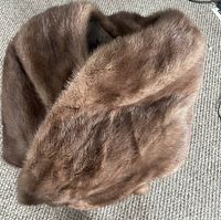 Brown fur shawl folded on carpeted floor showing plush texture and coloration