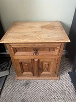 Front view of solid wood cabinet table showing drawer and double doors closed.