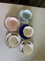 Top view of five teacups with matching saucers featuring different floral patterns and trims.