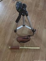 Mini tripod on wooden floor next to the extendable brass telescope with leather grip and case