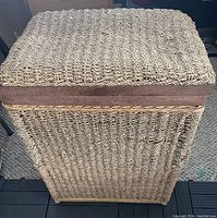 Top and side view of closed wicker hamper showing woven texture and solid framed lid.