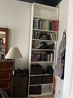 Tall white IKEA Billy bookshelf with two extensions, filled with books, baskets, and personal items, showing height and shelf details