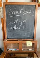 Photo of wooden framed chalkboard with writing 'Phone Messages call your mother!' and various chalk pieces in tray and compartments below.