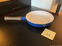 Side view of the blue Dansk saute pan showing the wooden handle and blue exterior.