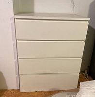 Front view of the white IKEA four-drawer dresser showing the drawer fronts and base.