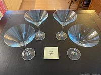 Top-down view of four clear glass martini glasses arranged on a table.