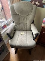 Front view of a light green cushioned glider rocking chair showing the padded seat, armrests, and high backrest.