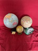 Three globes placed side by side on red fabric background, showing size comparison and bases.