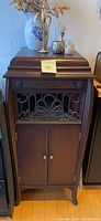 Front view of the full gramophone cabinet showing the dark wooden finish, decorative front grille, and double-door base section.