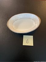 Oval bone china serving dish with silver/gray etched floral and scroll pattern, platinum edge visible, displayed against black background.