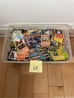 Large plastic bin filled with assorted Pokémon trading cards, showing several visible GX and regular cards on top including Lucario GX and Arcanine.