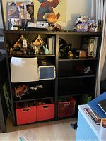 Photo of the black double shelving unit filled with various decorative items, storage boxes, and personal objects to illustrate shelf formatting and size.