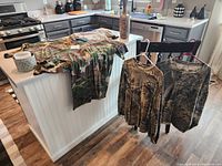 Five camouflage shirts displayed; three short sleeve and two long sleeve in XL size.