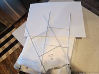 Several white corrugated plastic signs stacked with attached metal wire legs for ground placement, showing clean and unused condition.