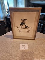 Framed black and white picture showing a cow in a clawfoot bathtub on a kitchen counter.