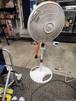 Front side view of the Lasko oscillating stand fan, showing the circular base, stand, and fan grille with center branding.