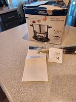 Photo showing the box of the Trudeau Multi Fondue Set along with instruction manuals and some forks in plastic wrapping on a kitchen counter.