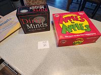 Photo showing Apples to Apples and Dirty Minds board game boxes on a counter.