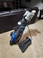 Full view of the black and blue stand golf bag with several golf clubs inside, showing the condition and overall appearance of the set.