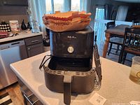 Front view of the Instant air fryer with basket pulled out and paper pan liners placed inside the basket.