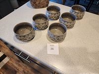Six beige ceramic bowls with cream decorative exterior pattern arranged on a counter