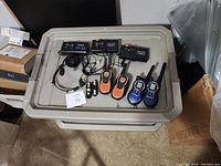 Lot of two way radios and accessories placed on a grey plastic storage container lid