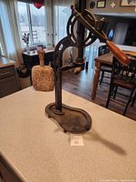 Side view showing the full height and base of the metal wine opener with wooden handle on a kitchen counter.