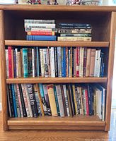 Front view of three wooden shelves filled with paperback and hardcover books