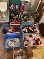 Six tubs of assorted holiday decorations arranged on floor