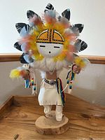 Front view of entire Kachina doll on wooden base in corner