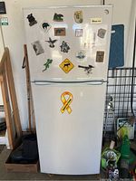 Front view of white Magic Chef two-door small refrigerator with various magnets on the doors.