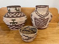 Front view of three Native American hand woven baskets showing size variation and geometric coiled patterns