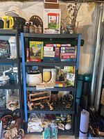 Wide view of black shelving unit with multiple shelves containing boxed games, puzzles, a Crosley radio, ceramic jars, wood wine rack, and various decor items.