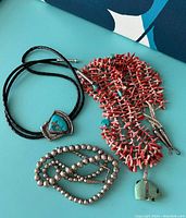 Overview of all three necklaces on teal background