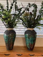 Front photo showing both vases side by side filled with greenery fakes, highlighting similar shape and glaze color