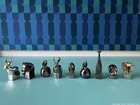 Nine silverplate Dansk animal figurines lined up, showing front and side profiles with tarnishing.