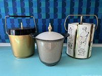 All three ice buckets shown together on a blue surface and blue geometric background.