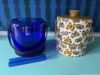 Blue translucent plastic ice bucket with matching tongs and handle, showing side view with slight surface crazing visible.