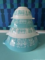 Stacked view of all four turquoise and white glass Pyrex bowls showing Amish Butter Print motif