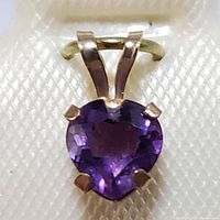 Close-up photo showing heart-shaped purple amethyst set in 10K yellow gold with four prongs and split bail.