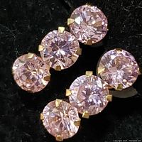 Close-up of two 10K yellow gold earrings each with three round cubic zirconia stones set vertically.