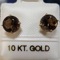 Close-up front view of both round smokey topaz earrings set in 10K yellow gold prongs on white background with '10 KT GOLD' text visible.