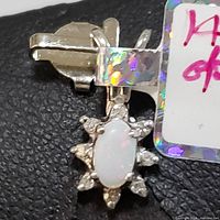 Close-up image showing the front view of the pendant with the oval opal center and surrounding diamonds set in 14K white gold.