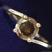 Close-up of ring face showing round brown diamond and prong setting