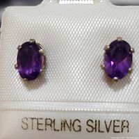 Front view of both sterling silver amethyst stud earrings presented on display card marked 'STERLING SILVER'