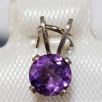 Close-up image of the sterling silver pendant showing the round faceted amethyst gemstone in a four-prong setting and the bail with two parallel bars.