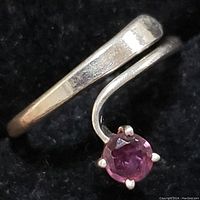 Close-up image showing the open end of the sterling silver ring with the round purple amethyst stone held by four prongs.
