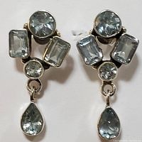 Close-up photo of the front of both earrings showing large round, rectangular and pear-shaped aquamarine stones set in sterling silver